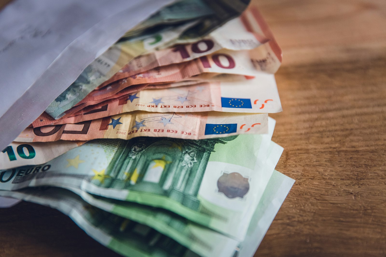 Billetes de euro de varios valores extendidos sobre una mesa de madera